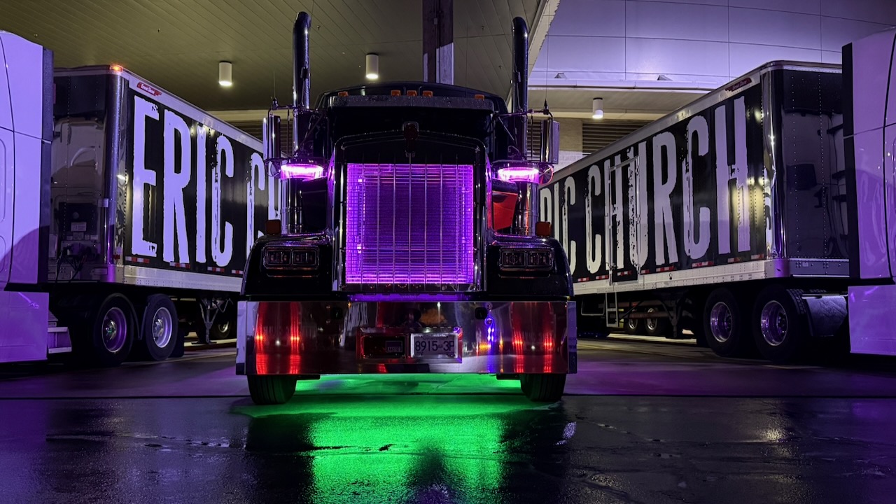 Running Turtle Kenworth with purple grille lighting between two Eric Church tour trailers inside a venue